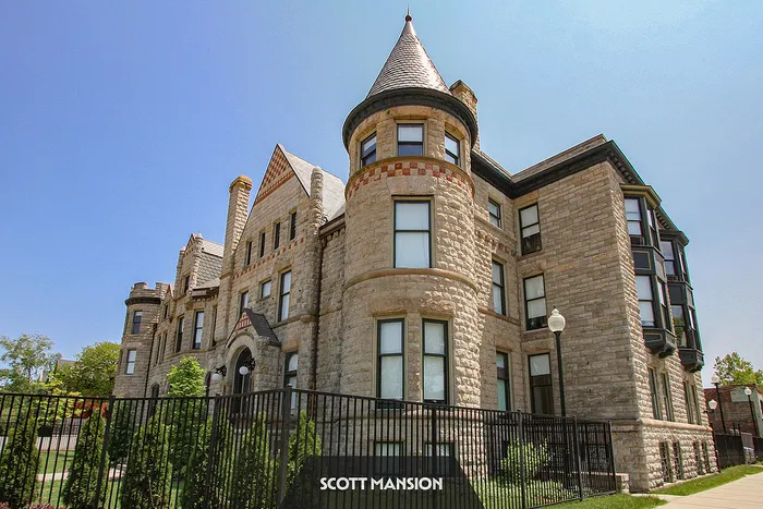 Majestic historic mansion with stunning stone facade and elegant architectural details under a clear blue sky.
