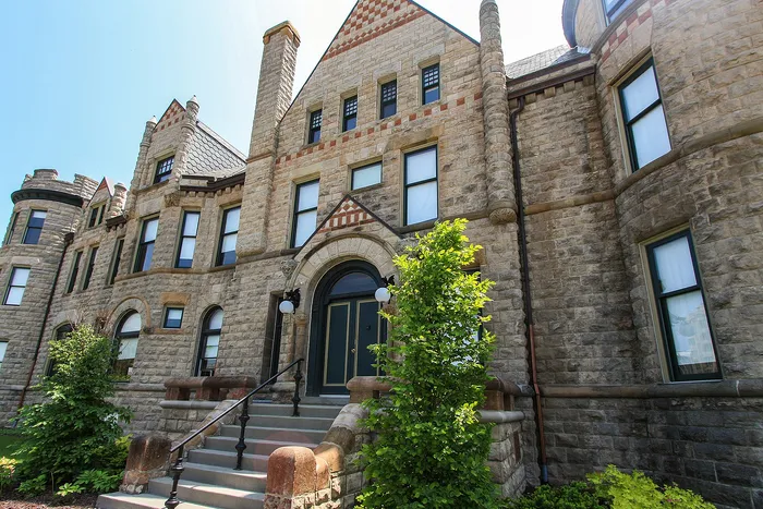Charming historic stone building with elegant arched entryway and lush greenery, showcasing timeless architectural beauty.