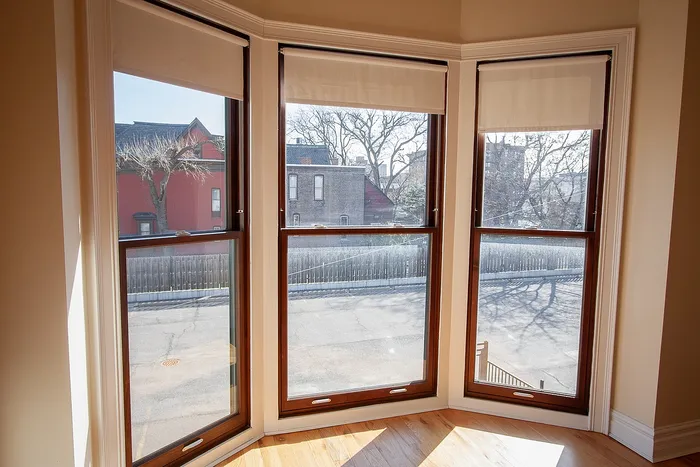 Bright corner nook with large bay windows offering a charming street view, perfect for a cozy reading spot.