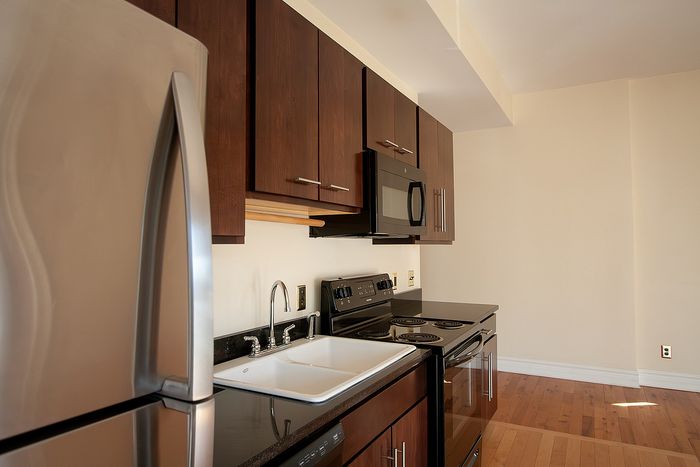 Modern kitchen with sleek stainless steel appliances, rich wood cabinetry, and elegant hardwood flooring.