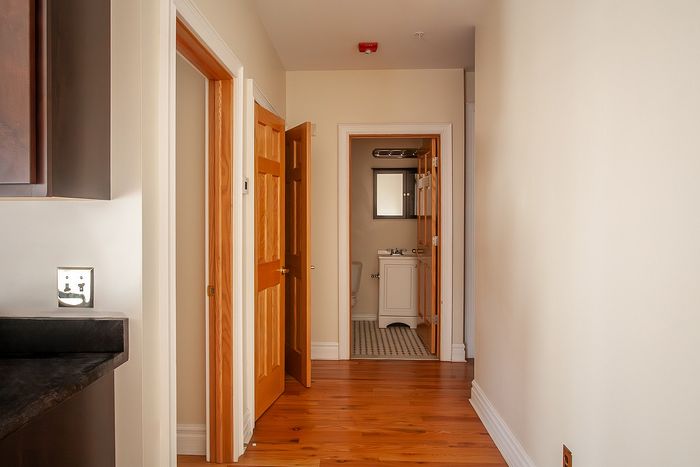 Inviting apartment hallway showcasing polished wooden floors and stylish bathroom entrance.