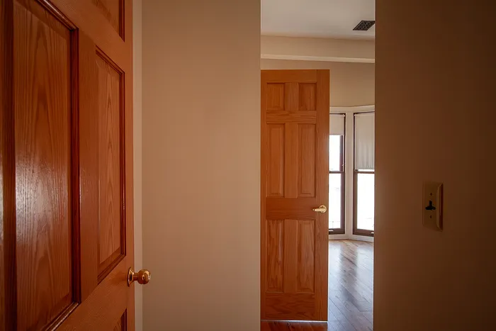 Inviting interior with elegant wooden doors opening to a sunlit room, featuring warm-toned walls and polished hardwood floors.