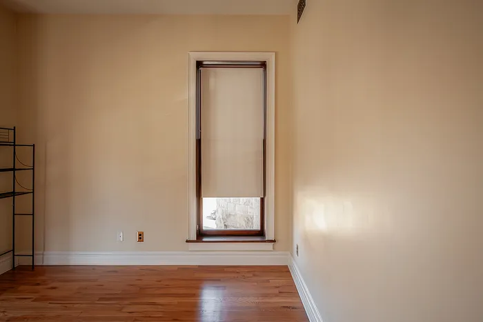 Bright room with elegant wooden floors and a large window showcasing natural light and warmth.