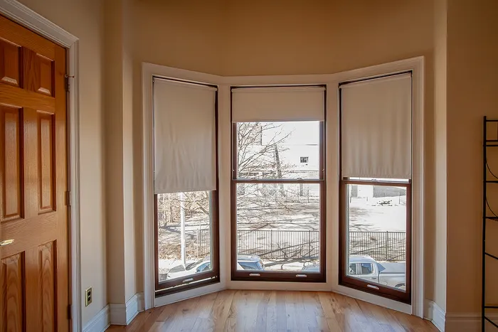Bright bay windows with natural light streaming into a cozy room, highlighting elegant wood accents and a serene outdoor view.