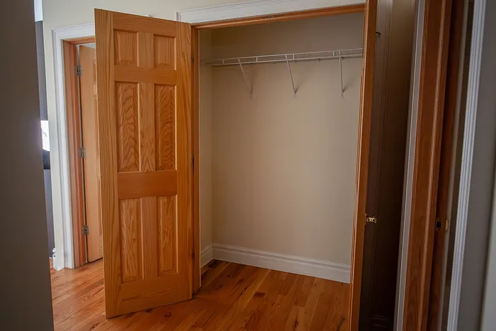 Inviting walk-in closet with rich wood flooring and ample shelving, ideal for organized living.