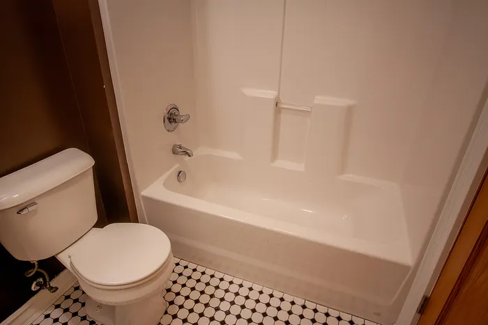 Elegant bathroom featuring a pristine white bathtub, modern fixtures, and stylish hexagonal tile flooring.