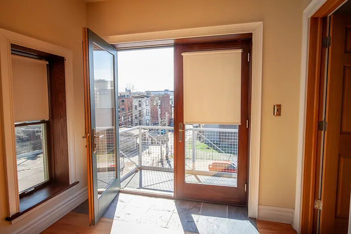 Bright and welcoming apartment view with elegant wooden French doors opening to a charming balcony overlooking the vibrant cityscape.