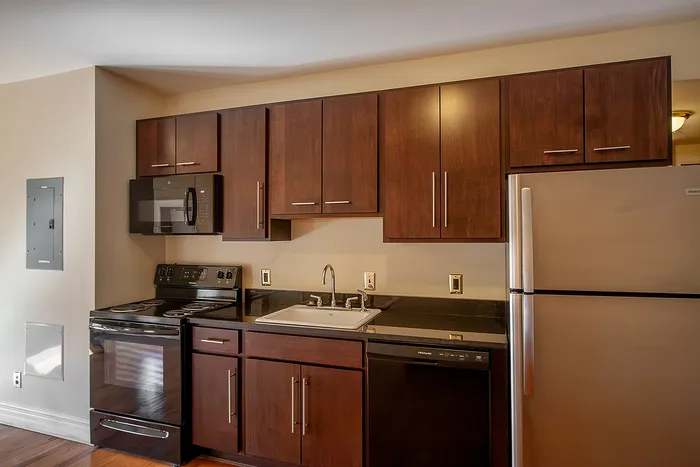 Modern kitchen with elegant dark wood cabinets, sleek countertops, and high-end stainless steel appliances including a microwave and refrigerator.