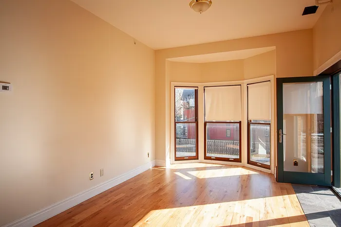 Bright and inviting room with elegant hardwood floors, large bay windows, and abundant natural light.