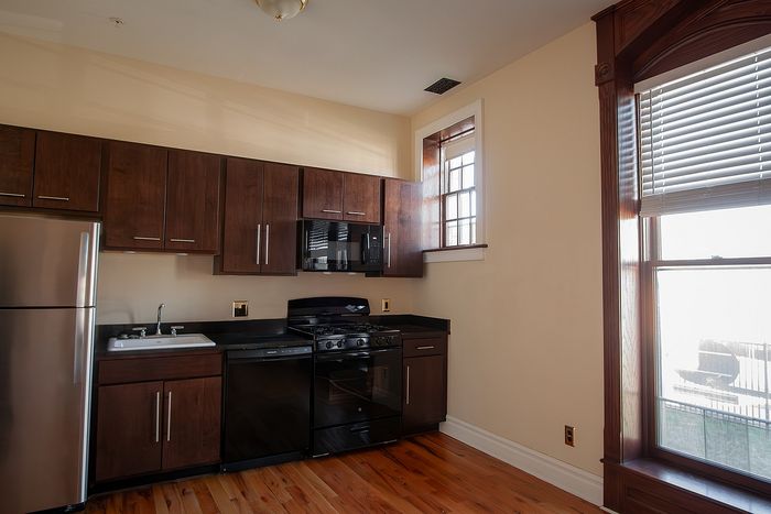 Elegant kitchen with modern appliances, rich wooden cabinetry, and large sunlit window for a warm ambiance.
