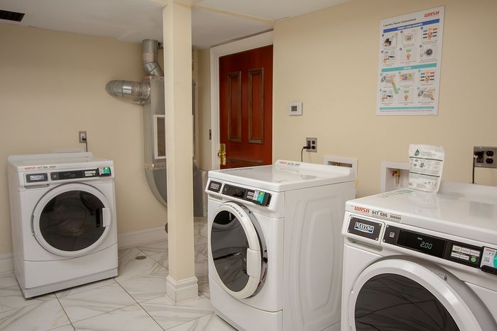 Modern apartment laundry room with high-efficiency washing machines on elegant tiled flooring.
