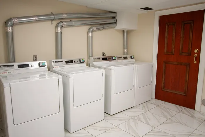 Efficient laundry room showcasing modern washing machines, elegant marble tile flooring, and sleek ventilation system.