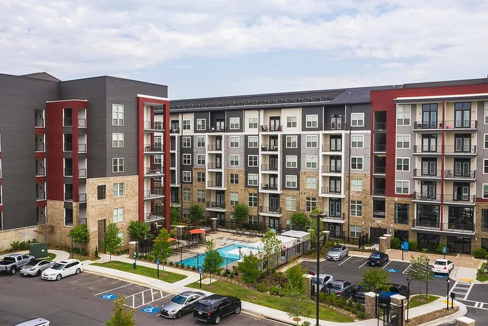 Modern apartment complex with stylish facade, featuring a pristine swimming pool and convenient parking area.