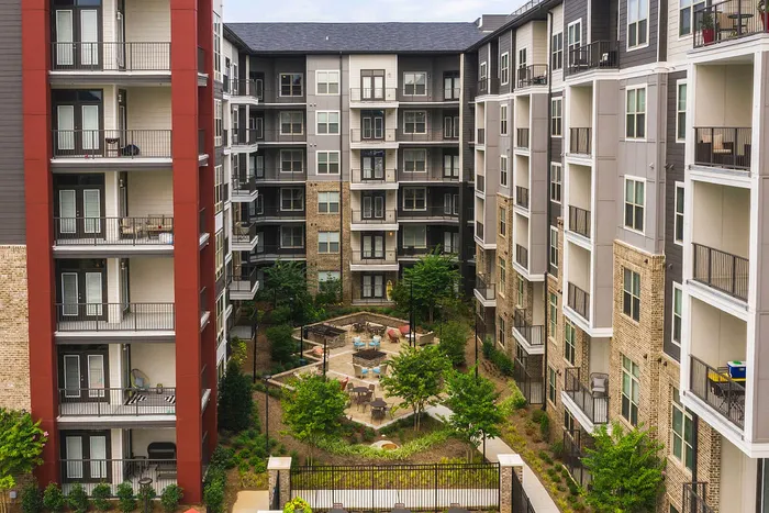 Modern apartment complex with stylish architecture featuring spacious balconies and a lush courtyard with inviting seating areas.
