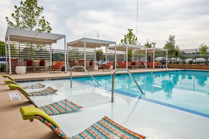 Inviting outdoor pool area with stylish lounge chairs and modern pergolas, perfect for relaxation and entertainment.