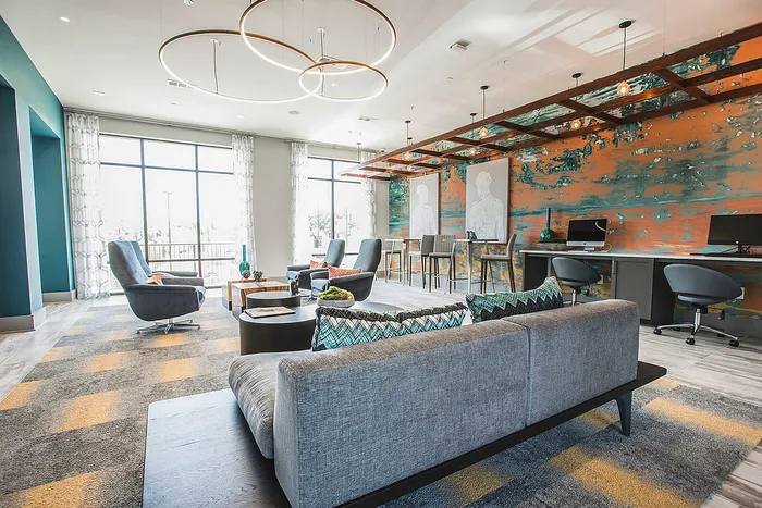 Chic and modern lounge area featuring comfortable seating, large windows, and a vibrant mural wall, perfect for relaxation and productivity.
