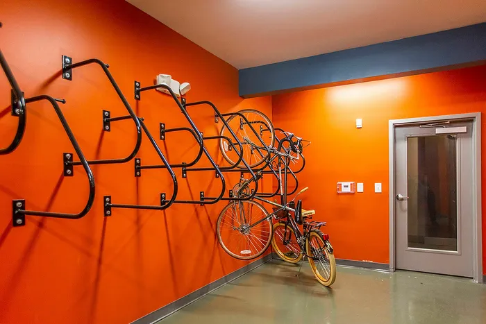 Vibrant orange bike storage room with modern wall-mounted racks, offering practical convenience for cyclists.