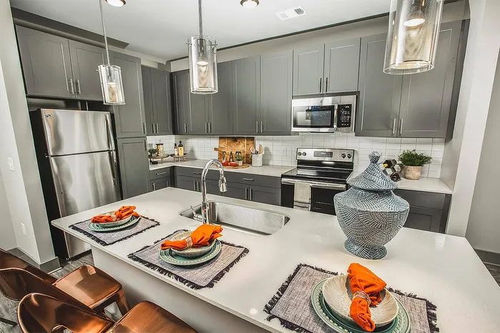 Modern kitchen with sleek gray cabinets, stainless steel appliances, and a stylish island with bar seating and vibrant decor.