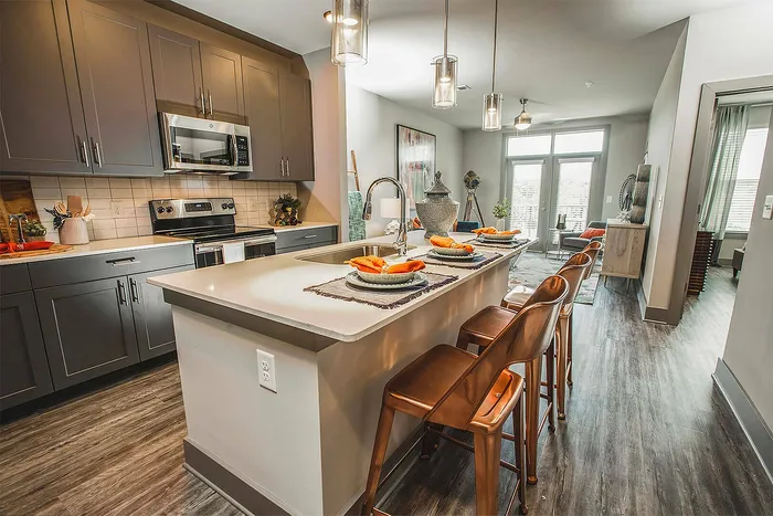 Contemporary kitchen interior boasting a sleek island with chic bar stools, elegant pendant lighting, and modern stainless steel appliances.