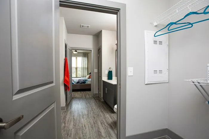 Inviting apartment hallway with wood flooring leading to a cozy bedroom, featuring ample natural light and modern finishes.
