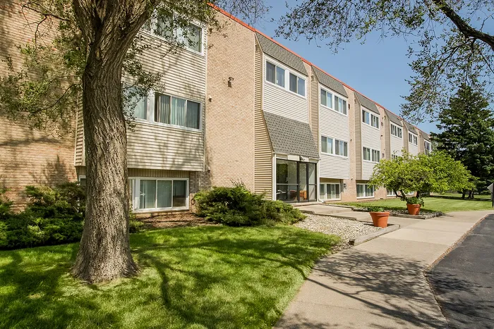 Charming apartment building surrounded by lush greenery and mature trees, offering a serene and inviting atmosphere.