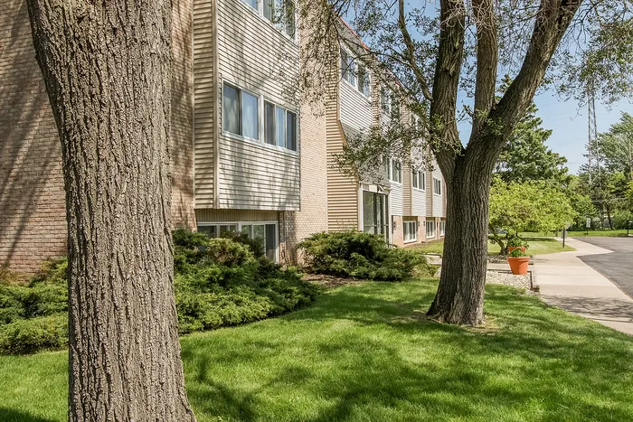 Charming apartment building surrounded by lush greenery and mature trees, offering serene living in a peaceful neighborhood.