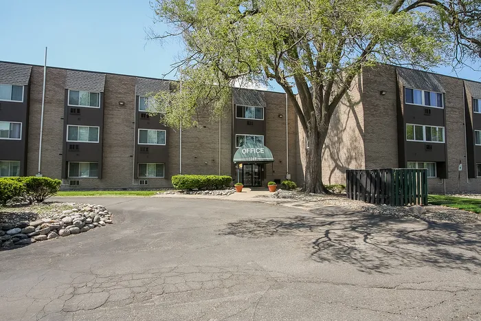 Inviting apartment complex with lush greenery and modern design featuring a central entrance.