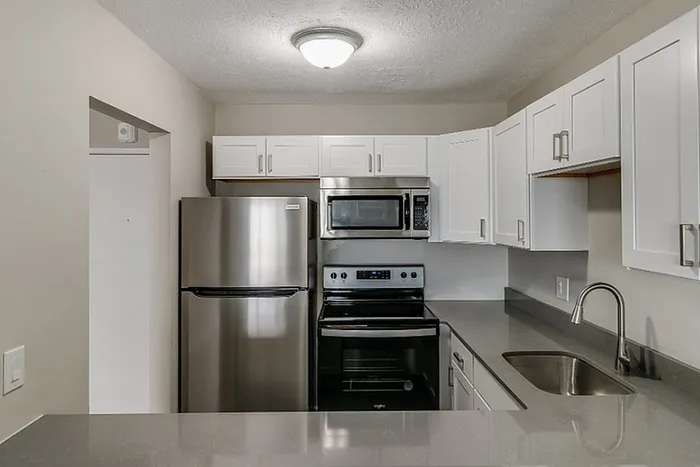 Modern kitchen with sleek stainless steel appliances, elegant white cabinets, and a polished countertop.