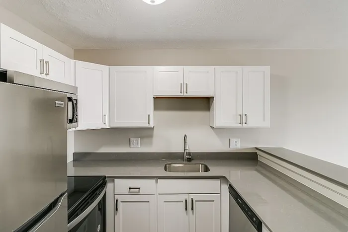Modern kitchen with sleek stainless steel appliances, pristine white cabinetry, and elegant gray countertops.