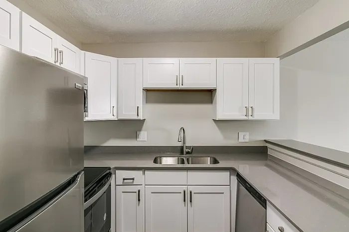Modern kitchen with sleek stainless steel appliances, elegant white cabinetry, and a polished countertop.