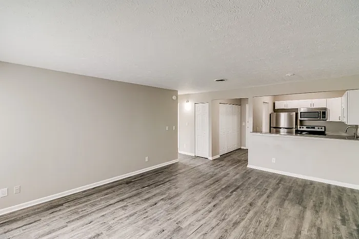Modern open-concept living area with sleek hardwood floors adjacent to a stylish kitchen featuring stainless steel appliances.