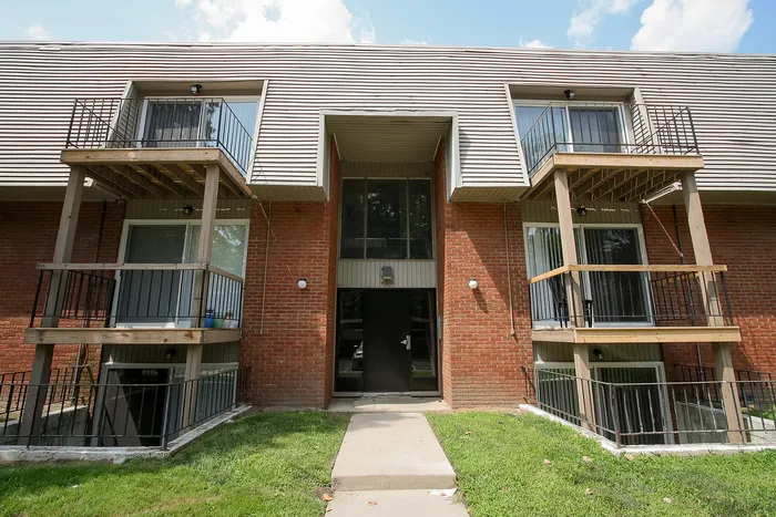 Charming brick apartment complex featuring private balconies, modern architecture, and lush green surroundings.
