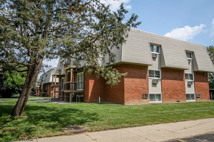Inviting apartment building with charming brick exterior and lush green surroundings.