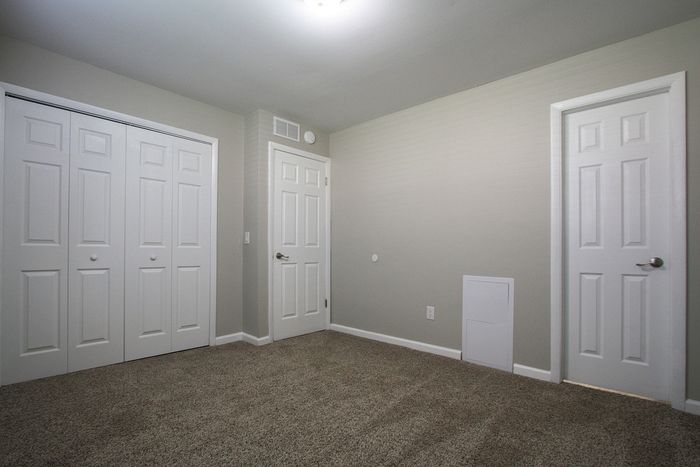 Bright and cozy room featuring plush carpeting, soft neutral walls, and ample closet space, perfect for a serene retreat or productive home office.