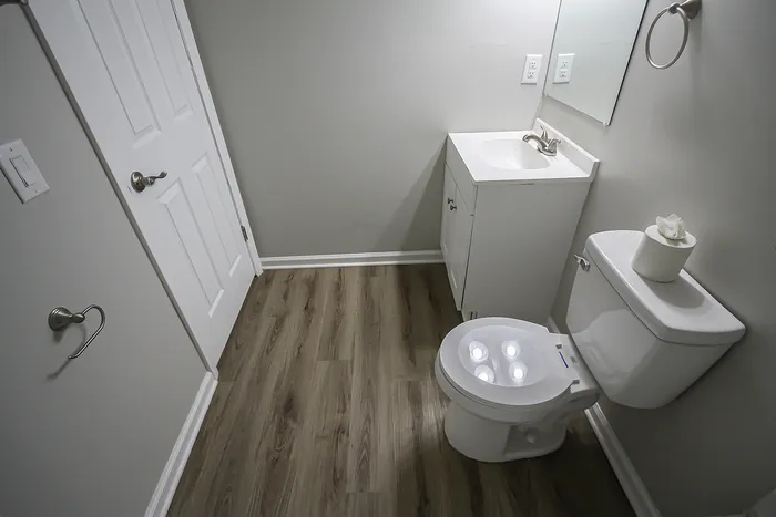 Bright and modern bathroom with sleek fixtures, elegant vanity, and wood-style flooring.
