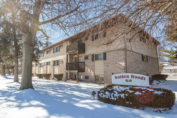 Charming two-story brick apartment building with balconies in a serene winter setting at Walden Woods.
