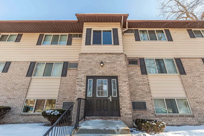 Charming brick apartment building with modern windows and inviting front entrance, nestled in a snowy landscape.