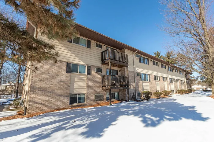 Charming apartment building with cozy balconies, surrounded by a serene snow-covered landscape and evergreen trees.