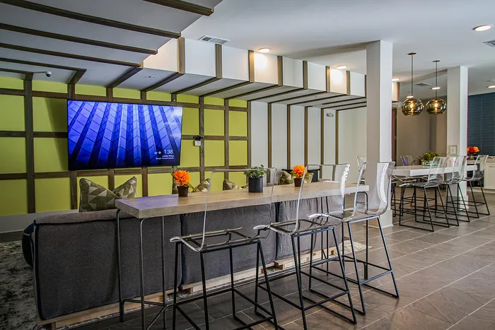 Modern lounge area featuring sleek acrylic bar stools, contemporary decor, and vibrant accent wall with mounted TV for entertainment.