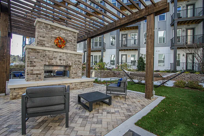 Charming outdoor living space with modern brick fireplace, cozy seating, and inviting pergola, perfect for relaxation and social gatherings.