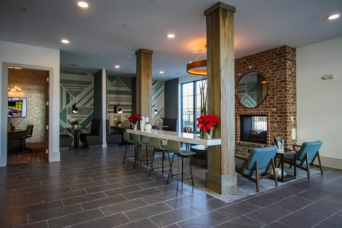 Modern communal lounge with stylish décor, elegant fireplace, and chic seating areas accented by vibrant red poinsettias.