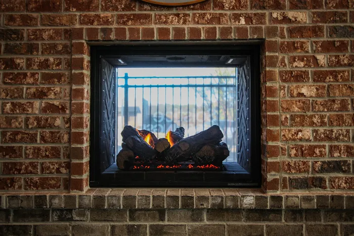 Cozy built-in brick fireplace with glowing logs adding warmth and charm to the space.