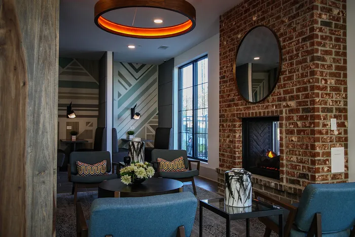 Cozy and stylish apartment lounge featuring a brick fireplace, modern seating, and chic decor.
