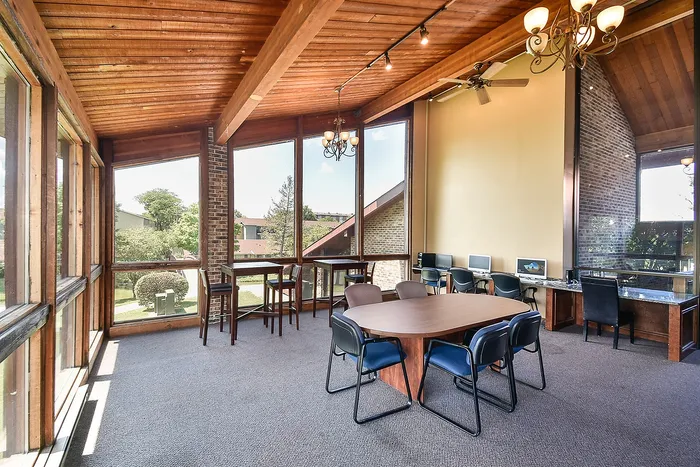 Bright, spacious room with large windows, wooden beams, and cozy seating, offering a perfect blend of natural light and elegance for gatherings or workspace enjoyment.