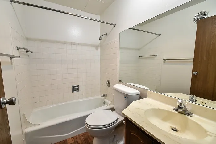 Elegant bathroom with a classic white bathtub, sleek vanity, and large mirror creating a bright and airy space.