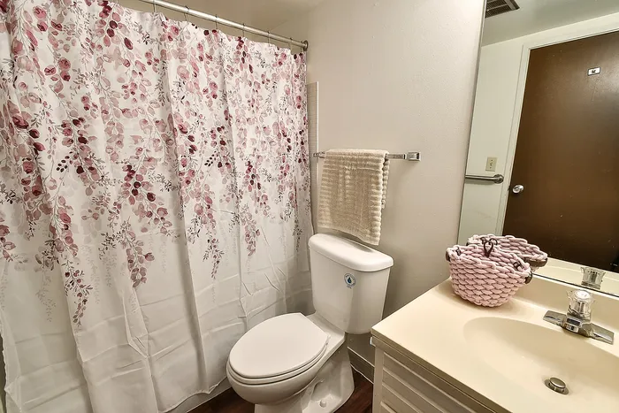 Charming bathroom with a floral shower curtain, modern fixtures, and soft beige accents for a serene feel.