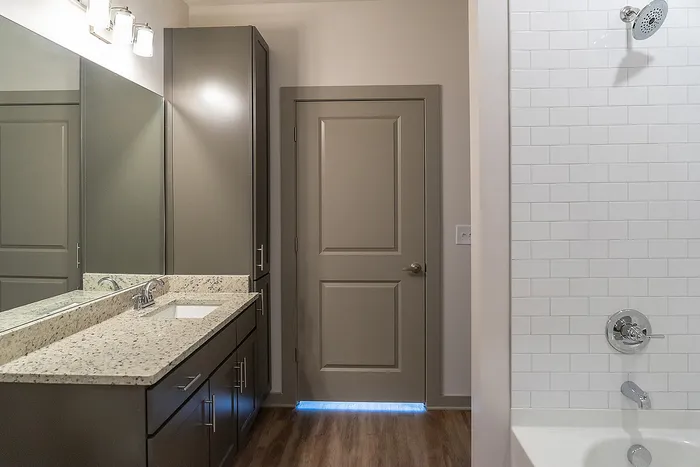 Elegant bathroom with granite countertop, sleek cabinetry, and modern shower featuring white subway tiles.