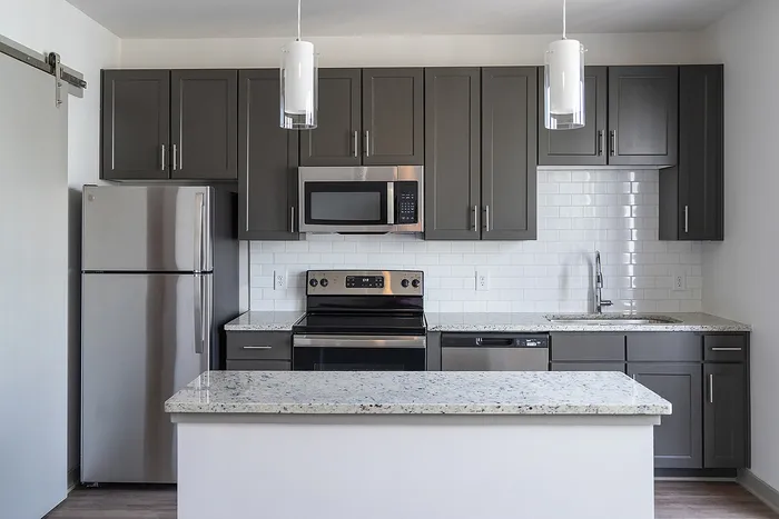 Modern kitchen with sleek granite countertops, stainless steel appliances, and chic gray cabinetry, featuring a stylish subway tile backsplash.