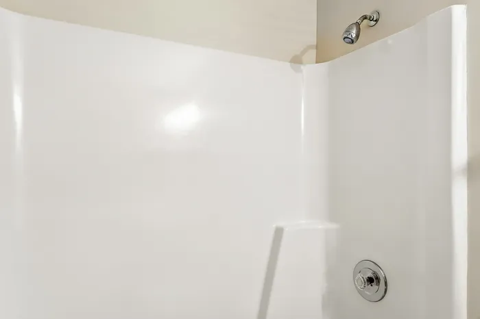Pristine white shower area with sleek chrome fixtures, perfect for a modern bathroom oasis.
