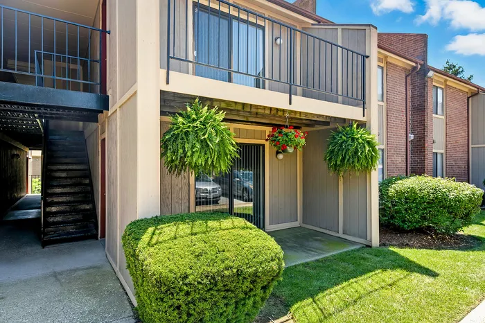 Charming apartment patio featuring lush hanging plants, vibrant flowers, and a cozy outdoor space, perfect for relaxation.